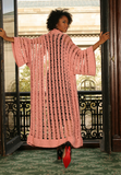 Sexy pretty woman wearing CharmaineLouise Intimates CLIntimates Diana pink cashmere crochet kimono robe black sheath dress heels standing in window